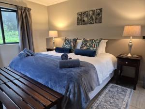 a bedroom with a large bed with blue pillows at Courtleigh Cottage in Hilton