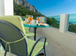 a balcony with a table with two glasses of orange juice at Villa Goldfield in Gradac