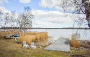 a dock with two chairs and a table and a boat at Sommarstuga med strandtomt in Ronneby
