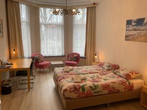 a bedroom with a bed and a desk and windows at Hotel Plato by Hofstad Studios in Scheveningen