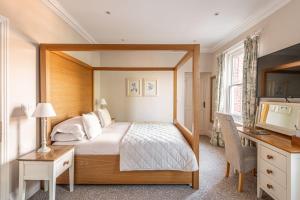 a bedroom with a bed and a desk and a television at Bartley Lodge Hotel in Lyndhurst +98 photos
