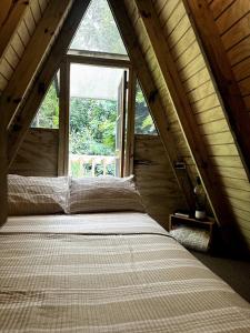 a bed in a room with a large window at Romantic Cozy Serene A Frame Mountain Cabin in Cayey