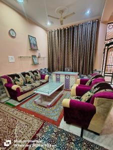 a living room with purple couches and a table at Vraja Kishori Sewa Dham in Vrindāvan