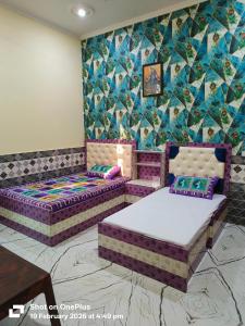 two beds in a room with a couch and a wall at Vraja Kishori Sewa Dham in Vrindāvan