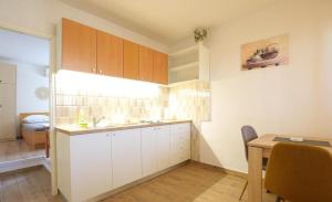 a kitchen with white cabinets and a table and a desk at Apartmani Suzi in Slatine