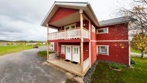 a red house with a balcony on a driveway at Riihen Pirtti in Äkäslompolo