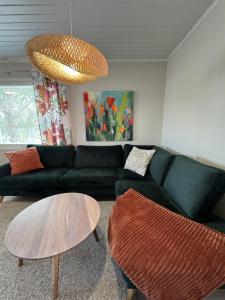 a living room with a black couch and a table at Riihen Pirtti in Äkäslompolo
