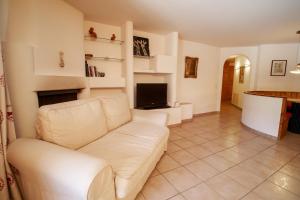 a living room with a white couch and a television at Chesa Foulla Rosa - Celerina in Celerina
