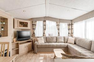 a living room with a couch and a tv at Camping Papillon Kinrooi 113 in Kinrooi