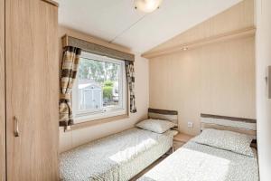 two beds in a small room with a window at Camping Papillon Kinrooi 113 in Kinrooi