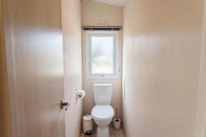 a small bathroom with a toilet and a window at Camping Papillon Kinrooi 113 in Kinrooi +11 photos