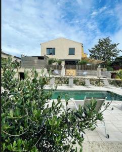a pool with chairs and umbrellas in front of a house at Le tipi d'Hamih in Uzès