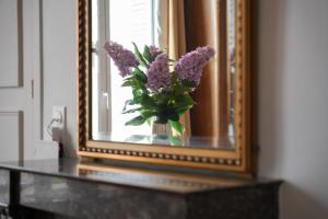 a vase of purple flowers on a table in front of a mirror at Maison bourgeoise, Rives du Cher, 14 pers in Montrichard