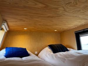 two beds in a room with a wooden ceiling at Slapen op de Dijk - Tiny House in Kraggenburg