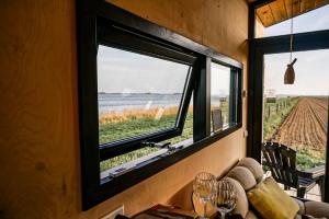 a room with a window with a view of a field at Slapen op de Dijk - Tiny House in Kraggenburg +13 photos