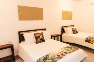 two beds in a room with white walls at Hotel Plaza Los Tucanes in Santiago
