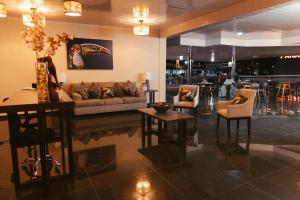 a living room with a couch and chairs and a bar at Hotel Plaza Los Tucanes in Santiago