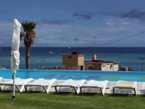a group of white lounge chairs next to a swimming pool at Sunset Cliffs Sol in Benidorm +19 photos