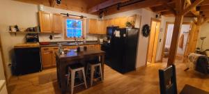 a kitchen with a black refrigerator and wooden cabinets at Ohana cabin in Hanover +9 photos