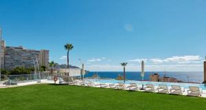 a swimming pool with lounge chairs and the ocean at Sunset Cliffs Sol in Benidorm