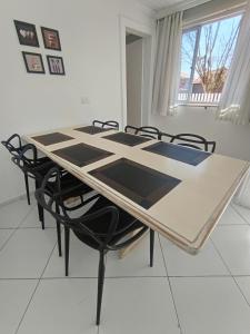 a dining room table with black chairs and a table at Bacacheri 5 Estrelas in Curitiba