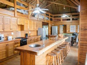 a kitchen with wooden cabinets and a large island with bar stools at Chicuanga in Chizavane