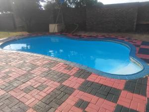 a swimming pool in a yard with a brick wall at Happy Guest House in Mahikeng