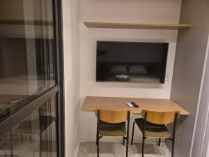 a small table with two chairs and a television on the wall at Apto Stúdio Liberdade novíssimo in São Paulo