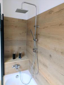 a shower in a bathroom with a wooden wall at Sauna Apartment Adelina Bad Wörishofen in Bad Wörishofen