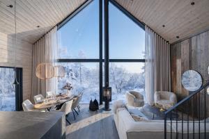 a living room with a table and chairs and a large window at AURA Arctic Chalets - Grand Panoramic & Grand Hideaway in Saariselka +68 photos