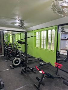 a gym with a green wall and several tread machines at Green Lodging House in Anda