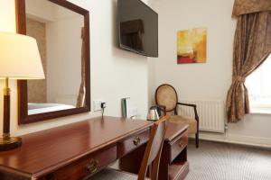 a hotel room with a desk and a mirror at George Hotel by Greene King Inns in Huntingdon