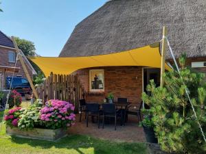 a yellow tent over a patio with a table and flowers at Tills Hüs in Utersum