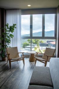 a living room with chairs and a table and a large window at Hotel PAUCHÉ Topiario Zapatoca in Zapatoca