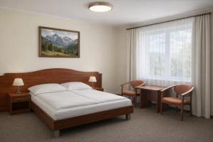 a bedroom with a bed and a desk and a window at Willa Park in Zakopane