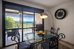a dining room with a glass table and chairs and a balcony at Duplex Palm Beach - Plage et Rando in Le Gosier