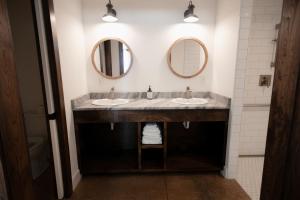 a bathroom with two sinks and two mirrors at New Field Farm at Timber Ridge in Lexington