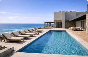 a swimming pool with lounge chairs and the ocean at Villa Apollo in Kionia