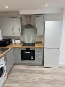 a kitchen with a white refrigerator and a dishwasher at Epsom High Street Apartment 6 in Epsom