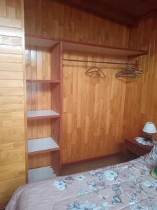 a bedroom with a bed with wooden walls and shelves at Cabañas Abrumax in Hornopiren +3 photos