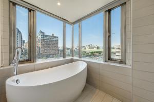 a white bath tub in a bathroom with windows at CHECK inn Taichung Wenxin Zhongqing in Taichung