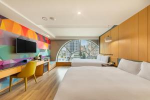 a hotel room with two beds and a desk and a tv at CHECK inn Taichung Wenxin Zhongqing in Taichung