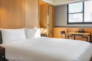 a bedroom with a large white bed and a window at CHECK inn Taichung Wenxin Zhongqing in Taichung