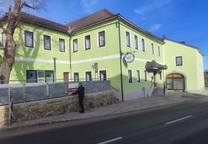 a man standing in front of a green building at Landhotel Max & Moritz in Liebenau