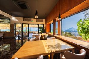 a restaurant with tables and chairs and a large window at Umine Annex in Beppu