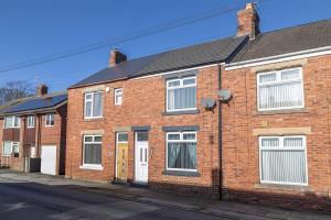 a red brick house with white doors and windows at The Relaxation Station in Bishop Auckland