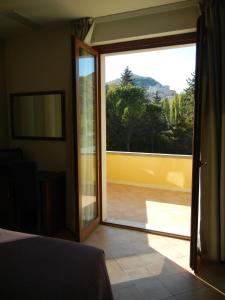a bedroom with a sliding glass door to a balcony at Hotel Dei in Cascia