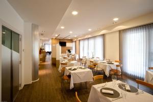 a restaurant with white tables and chairs and windows at Hotel Dei in Cascia
