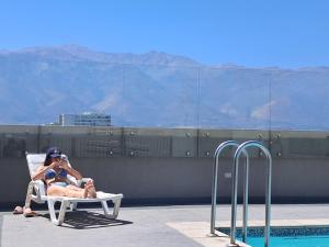 a man and woman sitting in a chair next to a pool at Plaza ñuñoa in Santiago