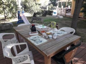 a wooden picnic table with white chairs around it at La bergerie in Chaillevette +4 photos